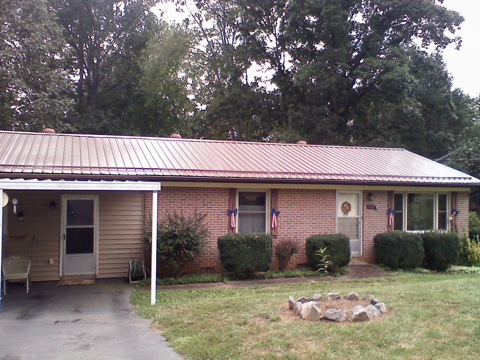 Bronze metal roof and carport on a brick ranch home — Roof Repair work by our crew in Greensboro