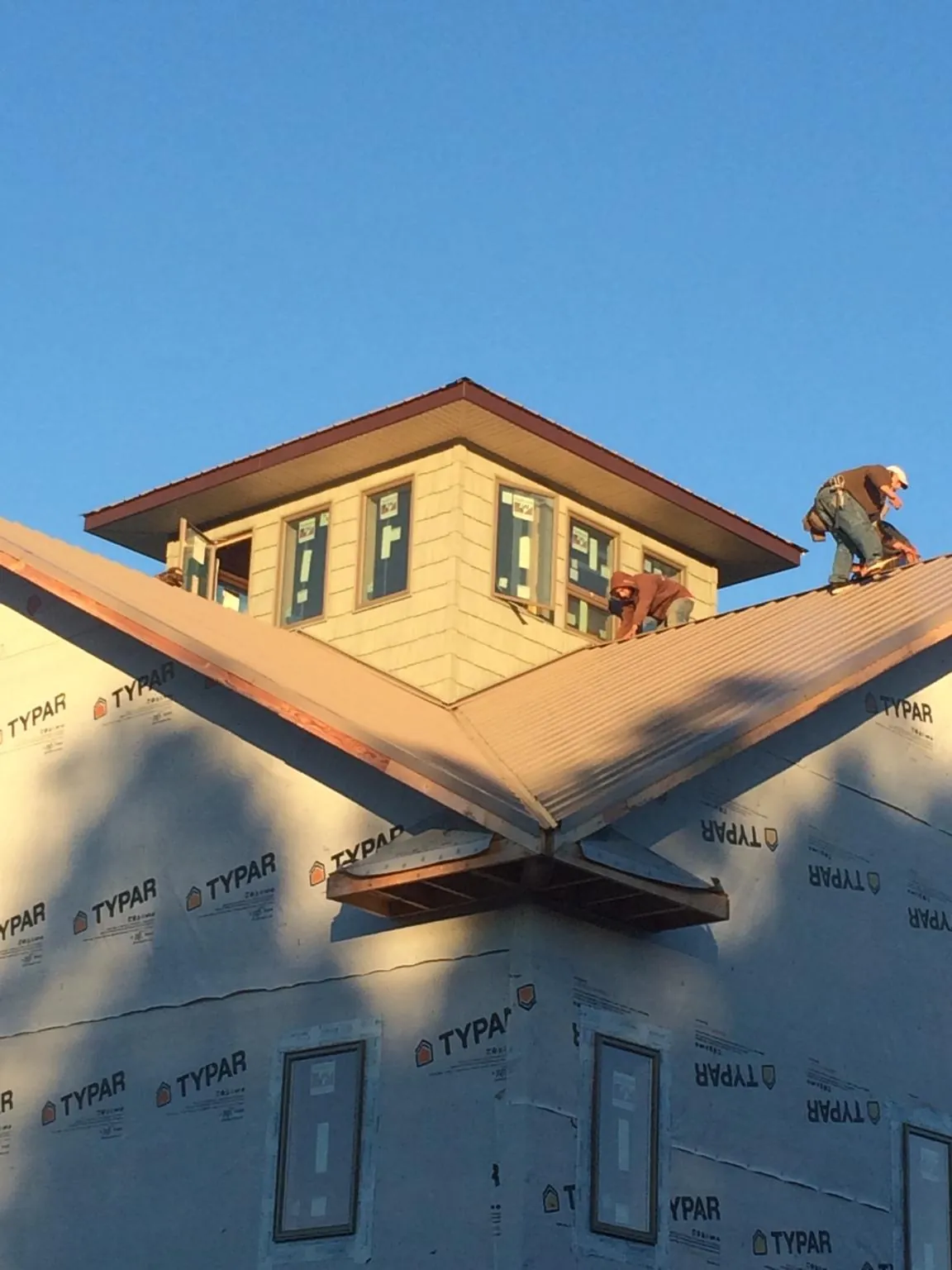 Roofers working around a rooftop cupola on a new metal roof at sunset — Roof Waterproofing in Greensboro by Roofing Brothers